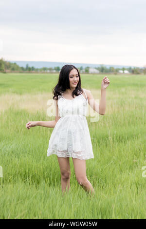 Young Woman Wearing White Dress While Standing On Grassy Field