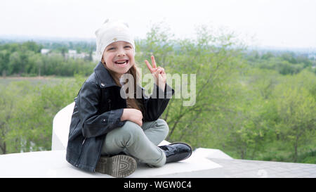 Lovely moments of little child enjoying walk in the city. Schoolgirl dressedtrendy denim urban casual outfit. Expressing true positive emotions of fas Stock Photo