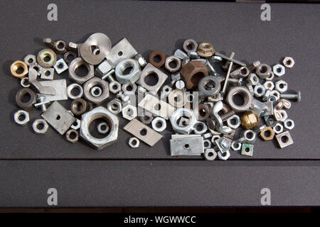 An odd assortment of metal nuts in different conditions with a mixture of a few bolts and odds and ends. Stock Photo