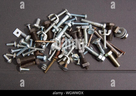 A collection of small metal bolts with a mix of nuts and an occasional screw. Stock Photo