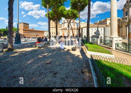 A woman listens to a street musician, or busker, as he plays guitar in front of the ancient Trajan's Forum in Rome, Italy Stock Photo