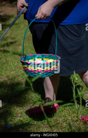 Blind woman carrying a cane and a colorful Easter basket filled with yellow, blue, green, purple, and pink eggs Stock Photo