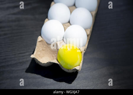 A carton of plastic Easter eggs with one egg missing and one colored yellow Stock Photo