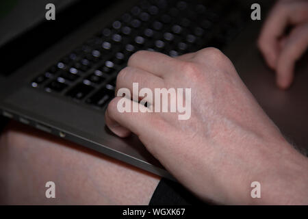 Man typing on a black and silver laptop keyboard Stock Photo