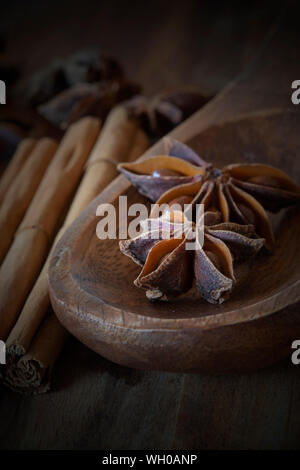 Star anise in wooden spoon with cinnamon on wooden chopping board. With lighting effect Stock Photo