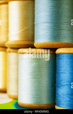 Different wooden spools of colored thread on  colored background , different shades of blue and yellow color  in every spool Stock Photo