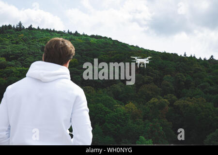 Handsome Young Adult Man Flying with Drone on the Public Roof Next of Forest Stock Photo