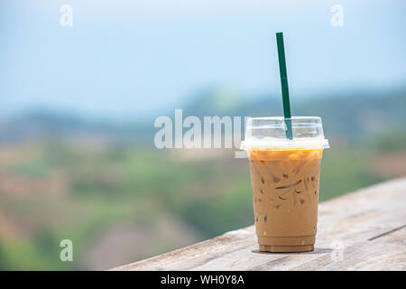 Glass of cold espresso coffee on the table Background blurry views tree and Mountain. Stock Photo