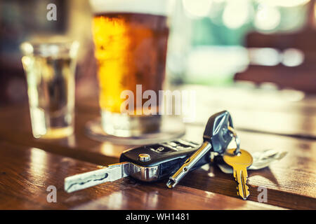 Car keys and glass of beer or distillate alcohol on table in pub or restaurant Stock Photo