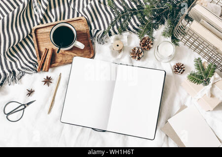 Christmas, winter composition. Blank greeting card, open diary, sketch book mock-up scene. Cup of coffee, old book, pine cones, fir branches, gift box Stock Photo
