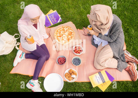 Top view of busy students eating pizza and drinking fizzy drink Stock Photo