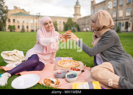 Cheerful muslim students enjoying pizza time outside Stock Photo