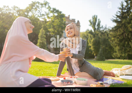 Muslim students drinking soda while having lunch outside Stock Photo