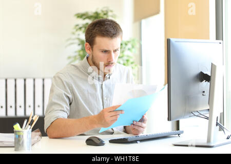 Shocked businessman checking documents with bad news at office Stock Photo