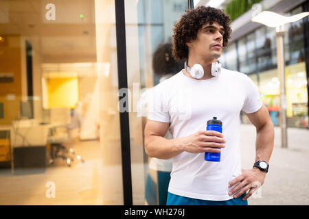 Handsome runner man drinking fresh water in urban area Stock Photo