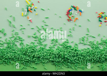 Green sprinkles on two tone green background with multi coloured sprinkles scattered - Green sprinkle background with space for text Stock Photo