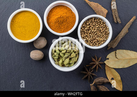 Spices in little white bowls on black slate background - Indian spice top view photo with space for text Stock Photo