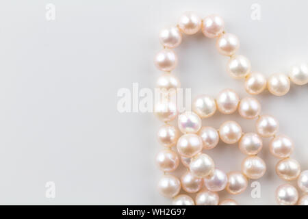 Pearl necklace with pink pearls in a string isolated on white background - Top view close up photograph of real oyster pearls Stock Photo