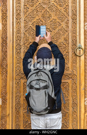 Tourist takes pictures of ornate door at Bibi-Khanym Mosque, Samarkand, Uzbekistan Stock Photo