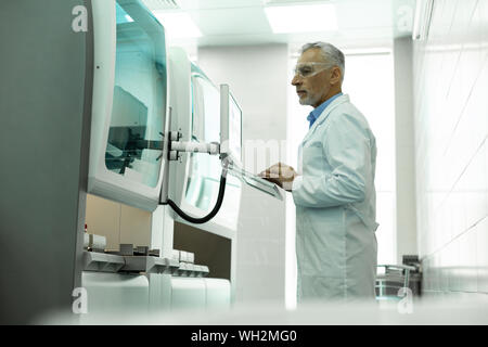 Concentrated scientist staring at screen of computer Stock Photo