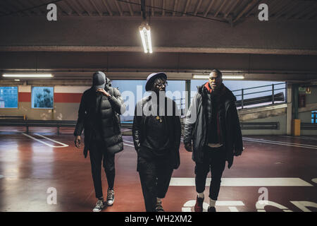 three young men walking parking lot - gang, crew, confident concept Stock Photo