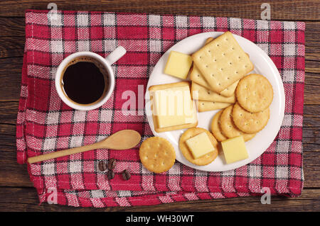 Cracker cookies with cheese and coffee cup on red tablecloth, top view Stock Photo