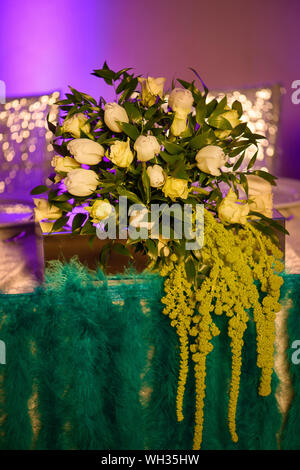 Vintage style floral arrangement or formal dining table centerpiece featuring a fresh bouquet of white tulips and roses mixed with waxy green leaves Stock Photo