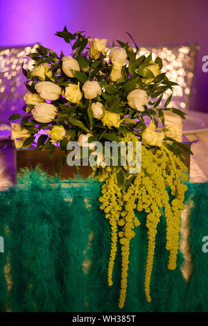 Vintage style floral arrangement or formal dining table centerpiece featuring a fresh bouquet of white tulips and roses mixed with waxy green leaves Stock Photo