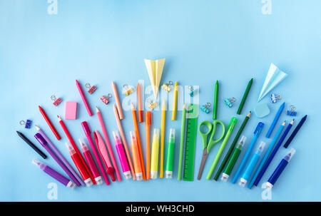 Variety of school supplies in rainbow colors sequence on pastel blue background. Flat lay style. Back to school concept. Stock Photo
