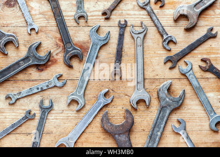 Old rusty wrenches on wooden background, flat lay top view industrial wallpaper