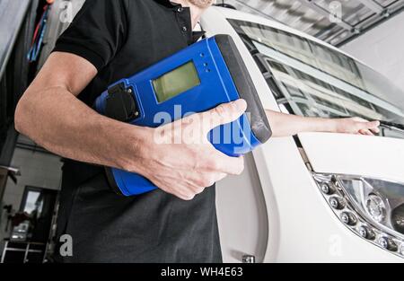 RV Repair Shop Worker with Appliance Tester. Refrigerator Troubleshooting. Recreational Vehicles Issues. Stock Photo