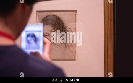 Visitor taking a photo of one of Leonardo Da Vinci's amazing drawings in London which marks the 500th anniversary of the death of Leonardo da Vinci. Stock Photo