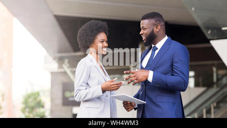 Two coworkers with digital tablet, discussing new project outdoors Stock Photo