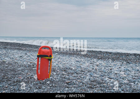 Lifeguard float in front of a stormy sea, rocky beach without tourists Stock Photo