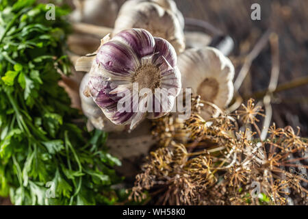 Garlic in basket with parsley herbs and dried dill on wooden table Stock Photo