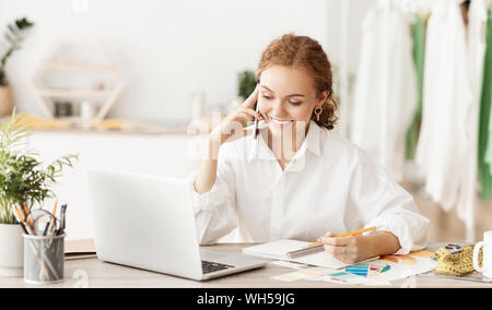 Fashion designer ordering fabric, talking on phone Stock Photo