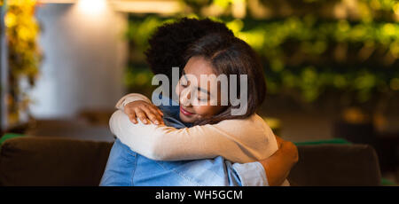 Teen mixed race girl hugging her boyfriend with eyes closed Stock Photo