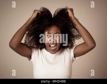 Portrait of frustrated african american woman with angry and stressed face. Looking crazy shouting and making furious gestures suffering anxiety. In H Stock Photo