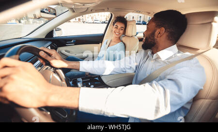 Happy afro couple talking in car during test drive Stock Photo