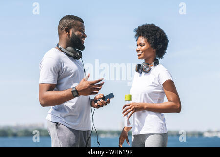 Black Couple Talking Before Morning Jog Along River Bank Stock Photo