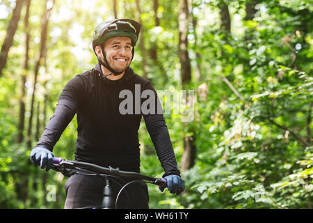 Joyful male bicyclist cycling in mountain forest Stock Photo