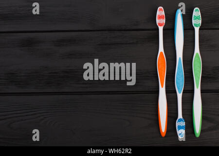 Colorful toothbrushes on black wooden background. Stock Photo