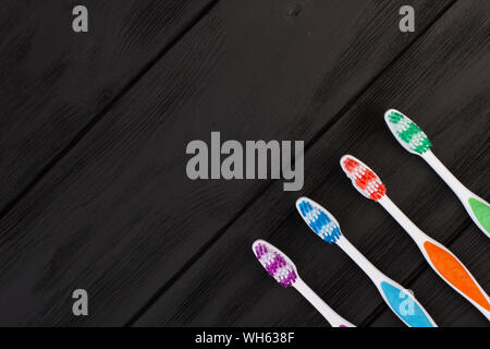 Multicolored toothbrushes on black background. Stock Photo