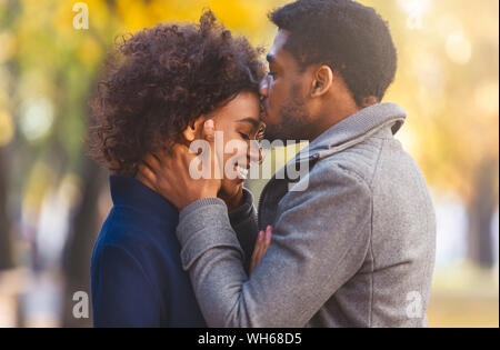 Portrait of sweet afro couple cuddling in the park Stock Photo