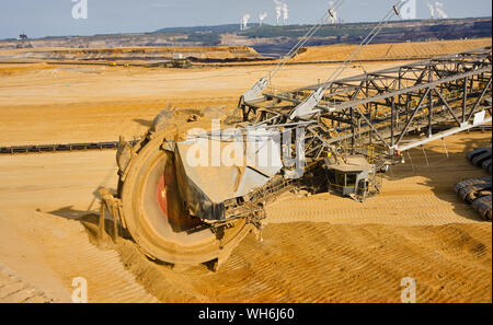 Giant bucket wheel excavator taking away the layers of ground before digging the brown coal. Largest open pit lignite mine in Europe. Power stations a Stock Photo