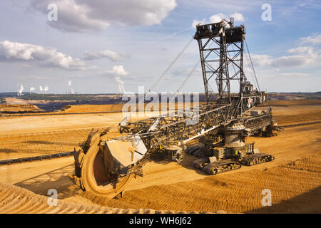 Giant bucket wheel excavator taking away the layers of ground before digging the brown coal. Largest open pit lignite mine in Europe. Power stations a Stock Photo