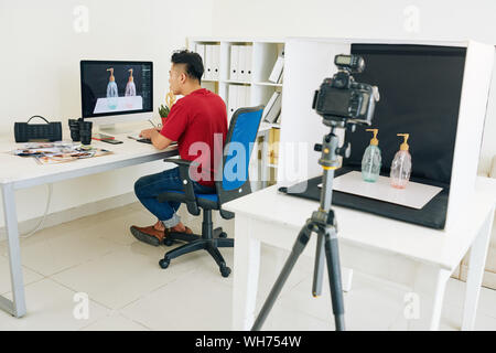Professional photographer retouching photos on computer at desk in his home studio Stock Photo