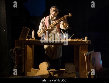 Violin maker as wooden figure at work in violin making workshop, Cremona, Lombardy, Italy Stock Photo