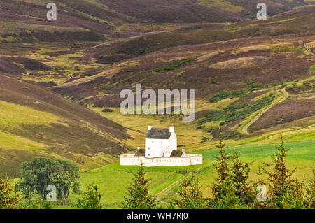 CORGARFF CASTLE ABERDEENSHIRE SCOTLAND THE WHITE STRONGHOLD SEEN FROM THE LECHT ROAD WITH PURPLE HEATHER ON THE HILLS IN LATE SUMMER Stock Photo