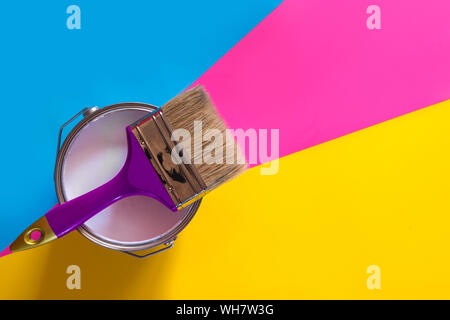 Purple brush with open can of white paint on blue and pink neon background. Trend concept. Stock Photo
